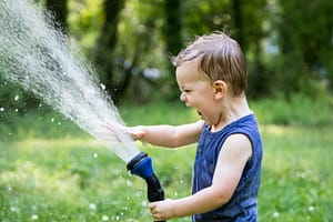 Boy playing in the yard with a hose